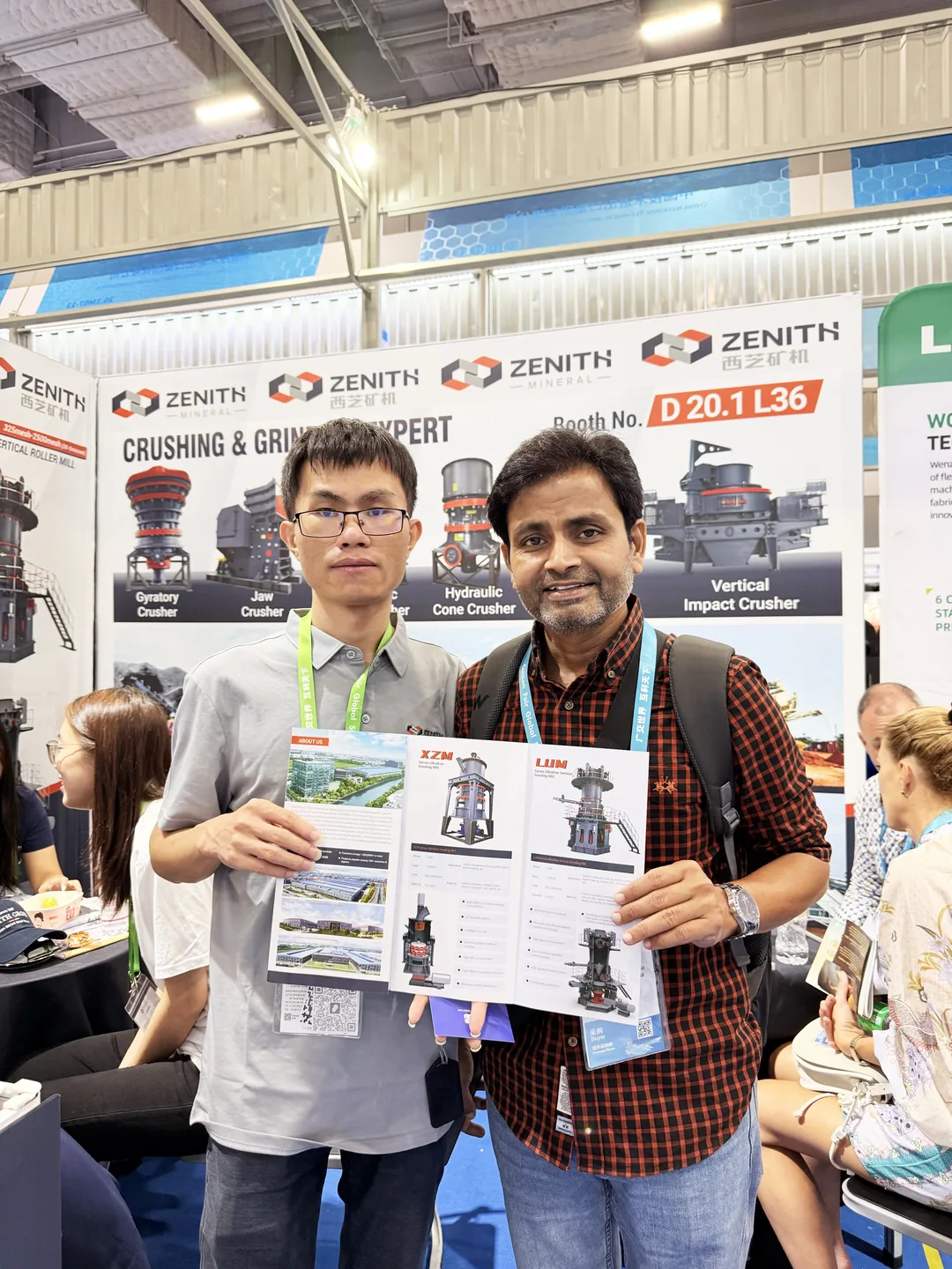 ZENITH team member with a visitor in front of the Booth No. D 20.1 L36 backdrop