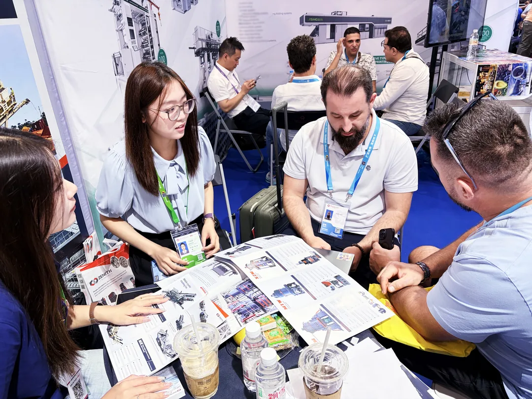 Visitors seated at the ZENITH booth reviewing grinding equipment literature