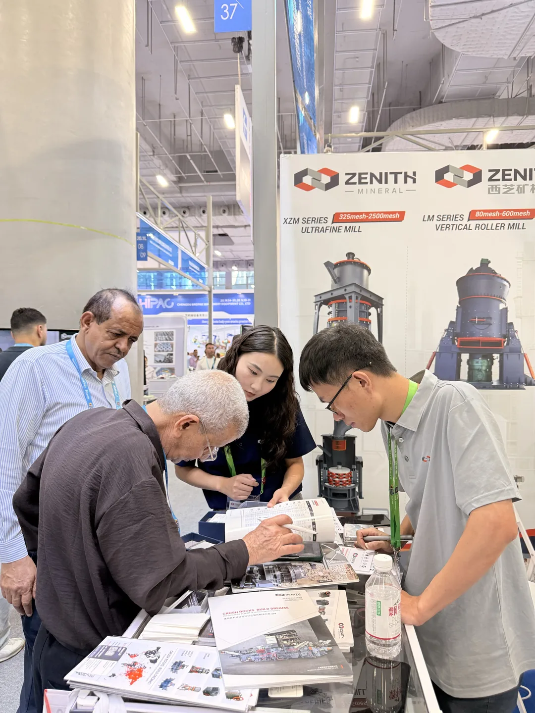 Visitor browsing product literature at the ZENITH booth, product wall in the background